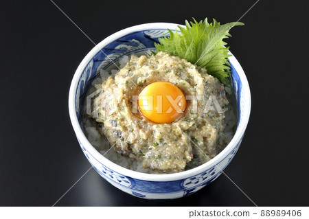 A bird's-eye view of a horse mackerel namero bowl topped with egg yolk on a black background 88989406