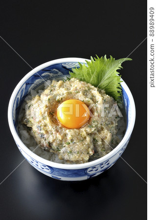 A bird's-eye view of a horse mackerel namero bowl topped with egg yolk on a black background 88989409