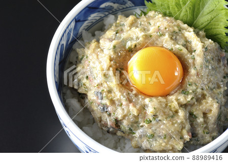 A bird's-eye view of a horse mackerel namero bowl topped with egg yolk on a black background A bird's-eye view of a horse mackerel namero bowl topped with egg yolk on a black background 88989416