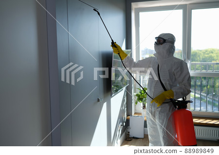 Worker in protective suit and face mask sprays chemicals indoors 88989849