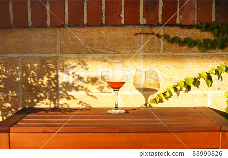 Glass of white wine on rustic wooden table and flower pots on terrace outside 88990826
