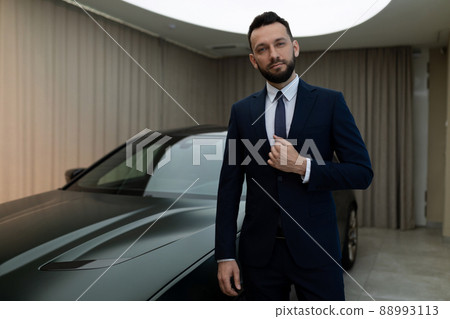businessman in a suit next to an expensive luxury car businessman in a suit next to an expensive luxury car 88993113