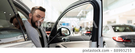 Pretty new car buyer peeking out of open car door 88993255