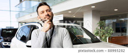 middle-aged man thinking about buying a new car middle-aged man thinking about buying a new car 88993282
