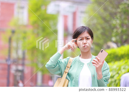 A woman holding a smartphone and sharpening her mouth and looking at the camera 1 A woman holding a smartphone and sharpening her mouth and looking at the camera 1 88993322