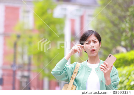 A woman with a facial expression who is having trouble holding a smartphone 1 88993324