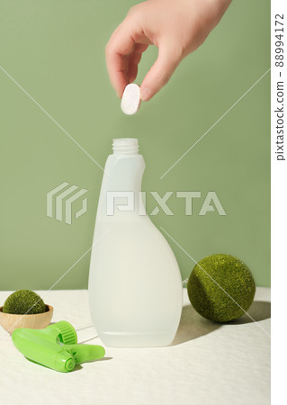 hand holding dissoluble tablet for kitchen cleanser refill. bottle of cleansing spray refilling. zero waste, refillable system. eco-friendly housekeeping. 88994172