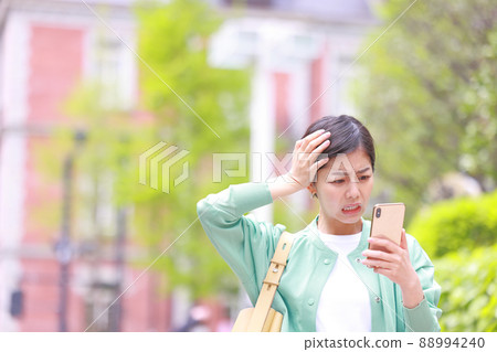 Woman holding her head and looking at her smartphone 2 Woman holding her head and looking at her smartphone 2 88994240
