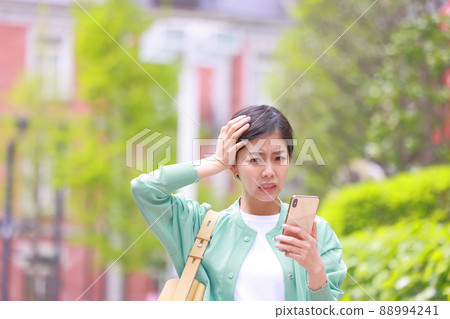 一個女人抱著頭,從她的智能手機上抬起臉 1 一個女人抱著頭,從她的智能手機上抬起臉 1 88994241