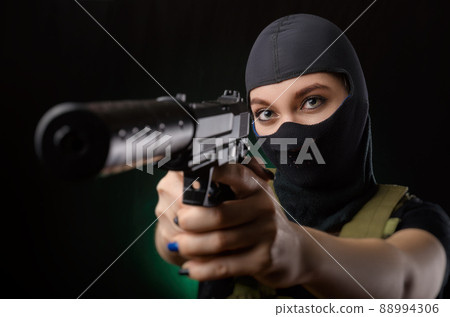 the girl in military special clothes posing with a gun in his hands on a dark background in the haze 88994306