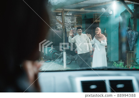 family coming home to their parent's house by car during idul fitri 88994388