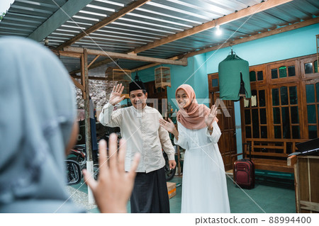 happy family welcoming guest to their house during eid mubarak 88994400