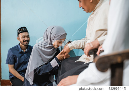 children visiting their parent and shake hand on idul fitri 88994445