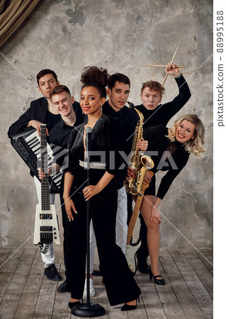 Portrait of diverse group of young people musical band playing with instruments - on gray concrete background. Portrait of diverse group of young people musical band playing with instruments - on gray concrete background. 88995188