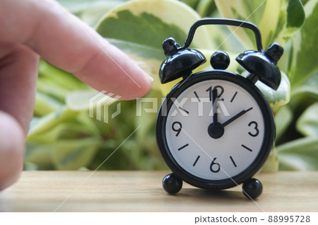 Hand pointing alarm clock that points at 2 pm. Copy space concept 88995728