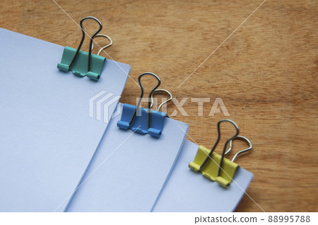 Blank white paper with clip binders on wooden table. Blank white paper with clip binders on wooden table. 88995788