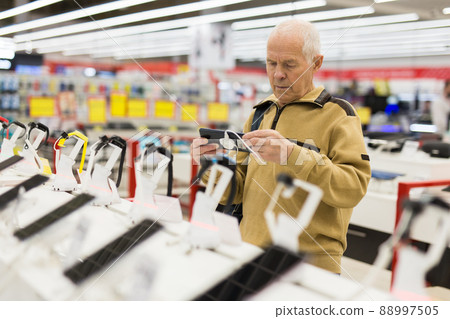 elderly man examines tablet computer in showroom of electronics store 88997505