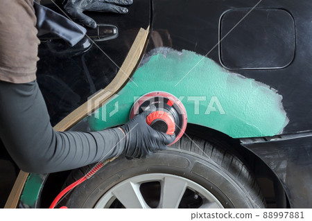 Hands of a painter who grinds a car for painting in a mechanical workshop. 88997881
