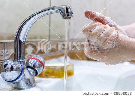 The girl washes her hands with soap under the tap with water. Personal hygiene. Disinfection. Hygiene concept. Corona virus Prevention to stop spreading coronavirus. The girl washes her hands with soap under the tap with water. Personal hygiene. Disinfection. Hygiene concept. Corona virus Prevention to stop spreading coronavirus. 88998038