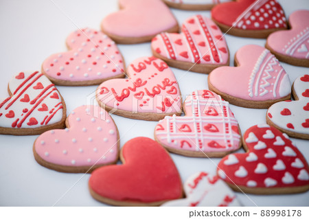 Top view homemade gingerbread Valentine's day with inscription - Love, cookies heart shapes decorated with colored royal icing and colorful patterns. Holiday food. Handmade patterns top cookies 88998178