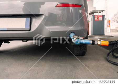 Person pumping gas. Fuel petrol for car at gasoline oil station nozzle in tank. Hand and black refueling gun close-up. Person pumping gas. Fuel petrol for car at gasoline oil station nozzle in tank. Hand and black refueling gun close-up. 88998455