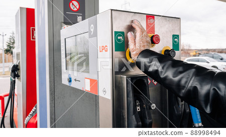 Gas station. Pump fuel petrol in tank car. Gasoline oil in nozzle. Close-up of the hand and the fuel gun. Blurred background. 88998494