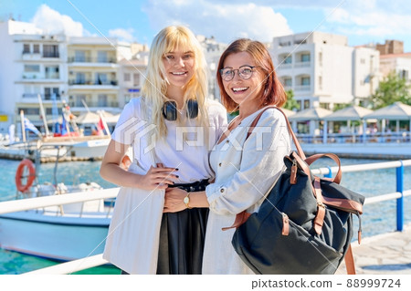Happy mother and teenage daughter together on the sea promenade. Happy mother and teenage daughter together on the sea promenade. 88999724