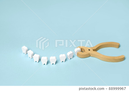 Tooth extraction with a dental instrument with forceps.  A model of teeth in the shape of a smile. Problems with wisdom teeth, toothache 88999967
