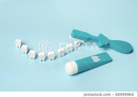 A toy tube of toothpaste and a toothbrush with a model of teeth standing in the shape of a smile. Dental health care, daily oral hygiene 88999968