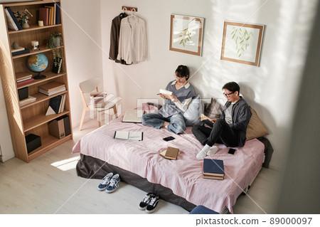 Asian student couple sitting on bed with books and preparing for exam together Asian student couple sitting on bed with books and preparing for exam together 89000097