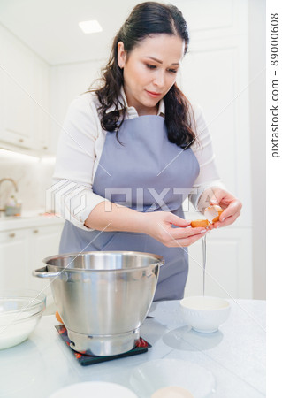 A woman breaks an egg and separates yolks from proteins 89000608