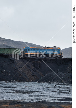 Freight train crossing polluted area with black sand hills as result of ecological catastrophe Freight train crossing polluted area with black sand hills as result of ecological catastrophe 89000633