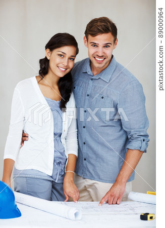 Attractive couple discussing house plans. Portrait of happy young couple smiling while discussing home renovation plans. Attractive couple discussing house plans. Portrait of happy young couple smiling while discussing home renovation plans. 89000964