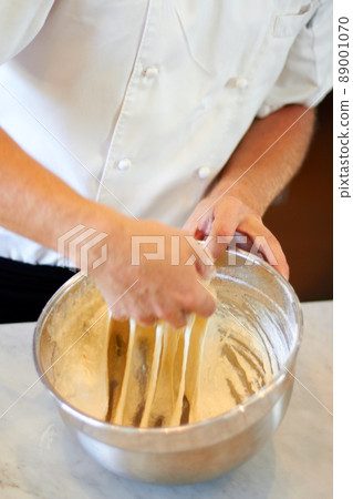 Dont go too far. Shot of a baker kneading dough in a bowl. Dont go too far. Shot of a baker kneading dough in a bowl. 89001070