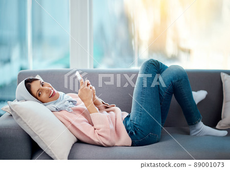 Connected from the comfort of my couch. High angle portrait of an attractive young woman sending a text while chilling on her sofa at home. Connected from the comfort of my couch. High angle portrait of an attractive young woman sending a text while chilling on her sofa at home. 89001073