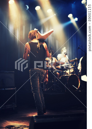 Rocking out. A guitarist on stage with his band beneath strobe lights in a nightclub. 89001155