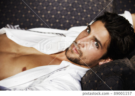 Radiating masculine confidence. Young attractive male, lying on a sofa looking at you with intensity. Radiating masculine confidence. Young attractive male, lying on a sofa looking at you with intensity. 89001157