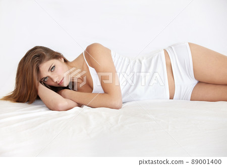 Seductive natural beauty. Portrait of a stunning young woman lying in bed wearing a sleepshirt and underwear. 89001400