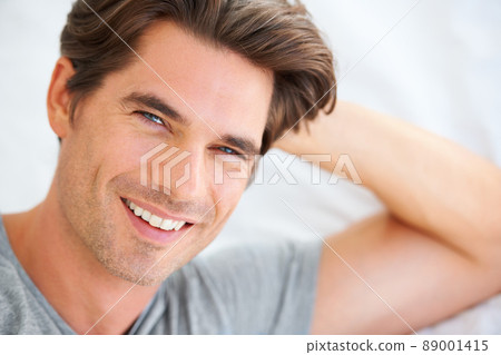 He is an early riser. Portrait of a handsome young man lying in bed and leaning on his hands. 89001415