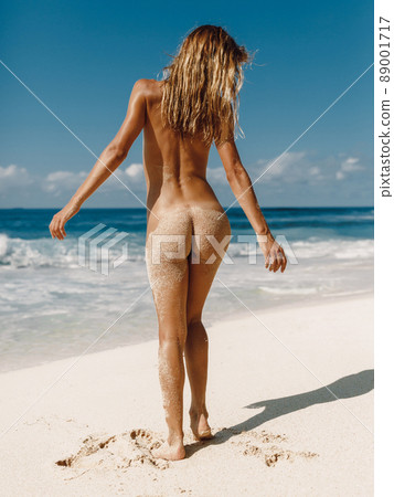 Naked woman posing at beach. Slim model with perfect body and wet skin Naked woman posing at beach. Slim model with perfect body and wet skin 89001717