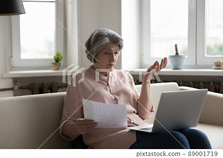 Older woman check utilities, experiences problems with payments looks concerned Older woman check utilities, experiences problems with payments looks concerned 89001719