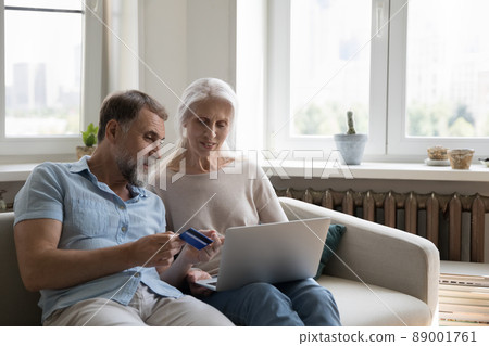 Older couple use laptop and credit card make purchase online 89001761