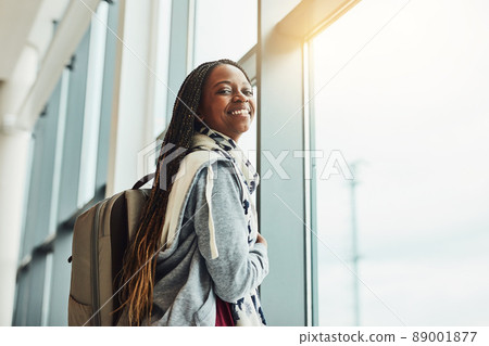 This will be my first time flying. Cropped shot of a young woman looking at out the airport window while waiting for departure. 89001877