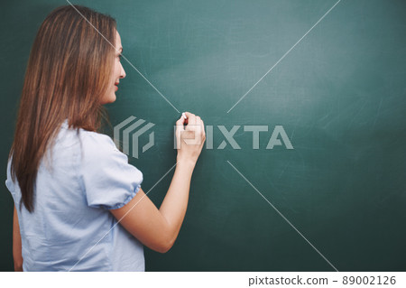 The lesson for today is.... A pretty young teacher writing todays lesson plan on the blackboard. The lesson for today is.... A pretty young teacher writing todays lesson plan on the blackboard. 89002126