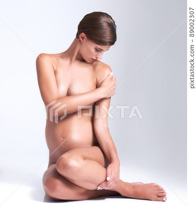 Sacred vessel. Attractive pregnant woman sitting naked in a studio. Sacred vessel. Attractive pregnant woman sitting naked in a studio. 89002307