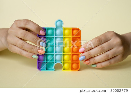 A woman holds a popular popit toy in her hands. Useful toys for the development of fine motor skills of the fingers. Anti-stress toy. entertaining games for children and adults. simple dimple. 89002779