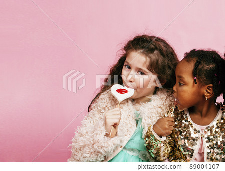 lifestyle people concept: diverse nation children playing together, caucasian boy with african little girl holding candy happy smiling 89004107