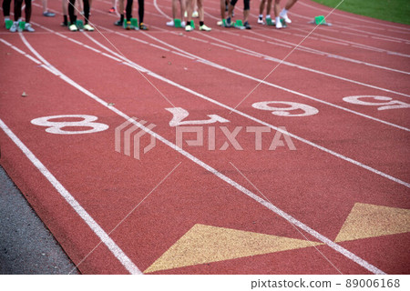 Runners at the starting line of an athletic racing track with lane markings 89006168