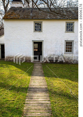 Idyllic path leads through grass to open door of whitewashed stone cottage Idyllic path leads through grass to open door of whitewashed stone cottage 89006178
