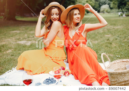 Beautiful girl in a red dress. Women sitting in a summer park. Beautiful girl in a red dress. Women sitting in a summer park. 89007442